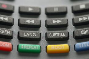 Black buttons on a TV remote. Two buttons are in focus and read lang and subtitle.
